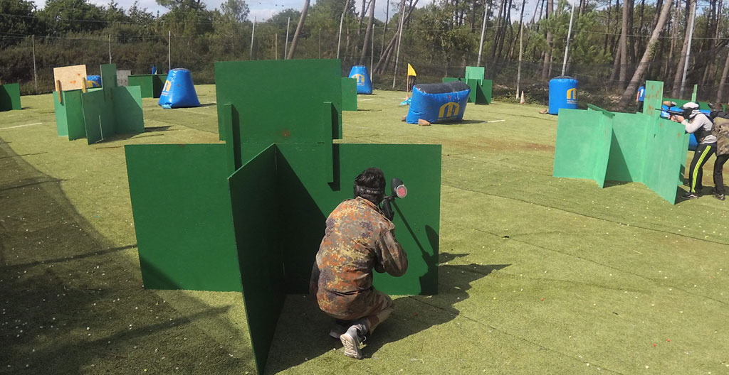 Illustration 3D isométrique de deux équipes de paintball s'affrontant sur un terrain avec bunkers et obstacles